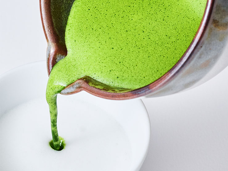 matcha being poured in a cup of milk